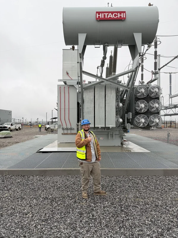 Giavanni Vigliotti at a hyperscale data center campus, standing beside a medium-voltage substation transformer in PPE.